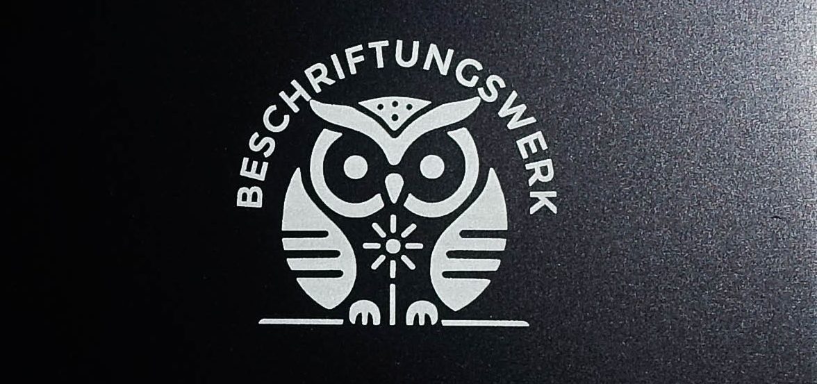 Schwarz eloxiertes Aluminium-Bauteil mit präziser Laserbeschriftung. Die Gravur erscheint in kontrastreichem Weiß.